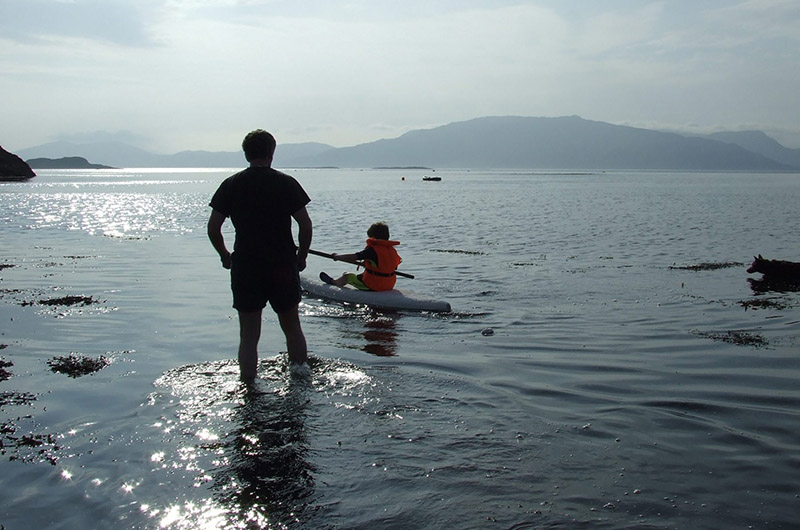 Father teaching son to paddle surfski